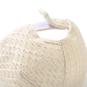 Detailed close-up of adjustable velcro strap and knitted texture on beige baseball cap