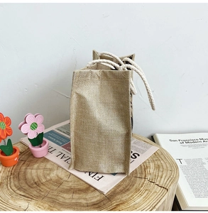 Close-up of small jute bento bag with durable cotton rope handles on a wooden base