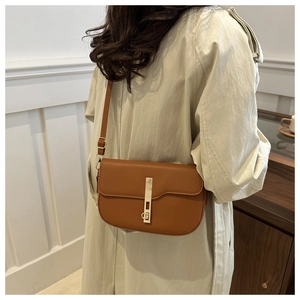 Close-up of caramel brown leather saddle bag featuring a stylish metal bar buckle closure