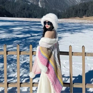 Close-up of a white faux fur hood and colorful knitted shawl wrap in a snowy forest setting
