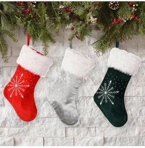 Trois chaussettes de Noël en peluche avec flocons de neige en rouge, argent et vert foncé