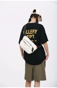 Close-up of white minimalist crossbody chest bag featuring contrast orange brand label