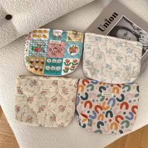 Close-up of four quilted cotton makeup bags with floral and geometric cartoon patterns