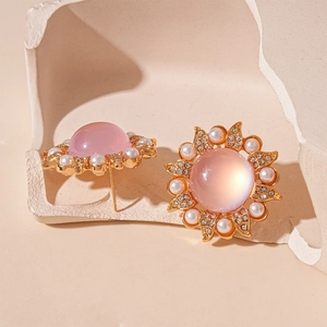 Detail of sunflower stud earrings with pink gemstone, pearls, and crystals on a stand