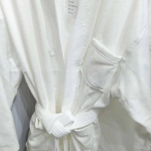 Close-up of white cotton hotel bathrobe featuring a red letter R embroidery on the pocket