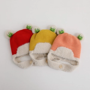 Close-up of three knitted winter hats with faux fur earflaps and plush pom-poms