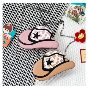 Detail of cowboy hat shaped crossbody bags with cow print and star accents in a cute setting