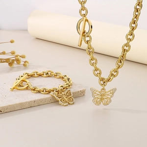 Detail von goldenen Schmetterlingsketten mit Strass und Knebelverschluss auf einer Steinplatte