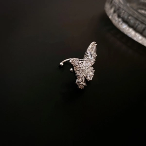 Dettaglio di un ear cuff a farfalla d'argento con zirconi lucidi su sfondo scuro