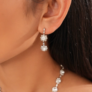 Close-up of sparkling silver flower earrings with zircon stones on an elegant model
