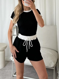 Detail of black knit two-piece set featuring ribbed texture and white drawstring accents