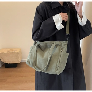 Detail of olive green corduroy tote bag featuring external pockets and a sturdy shoulder strap