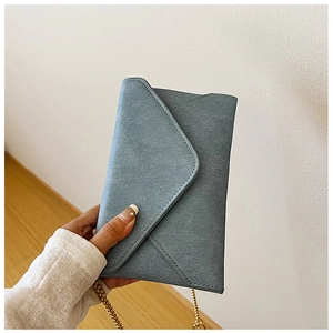 Detail of blue envelope bag with cross-grain texture and gold metal chain strap