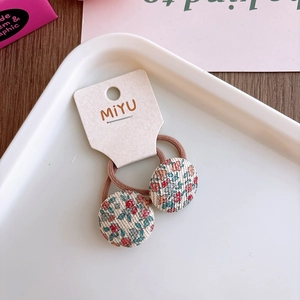 Detalle de gomas de pelo con botones florales para niñas en tarjeta de soporte