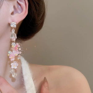 Detail shot of tassel flower earrings with crystals and pink petals on female model