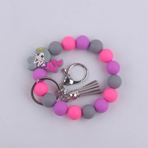 Detail of pink and purple silicone beaded wristlet with gray mermaid charm and silver ring