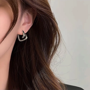 Close-up of minimalist silver twisted heart earring worn by a model in profile view