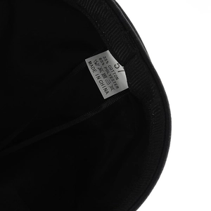 Detail of internal washing label showing material composition and size 57 on a black cap