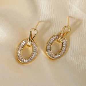 Elegant gold-plated oval stud earrings with micro-set zircons on champagne silk fabric