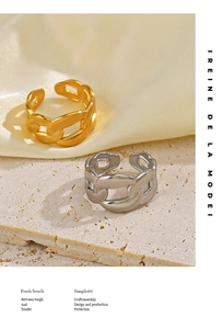 Detail of Cuban chain link rings in gold and silver finishes on a stone surface