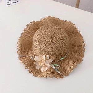 Detail of child straw hat with wavy brim, cream flower, and iridescent ribbon trim