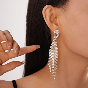 Macro detail of long silver fringe earrings with shimmering white rhinestones on model