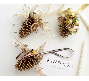 Detail of Christmas pinecone ornaments with gold bells, ribbons, and festive orange slices