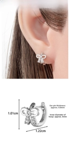 Close-up of silver bow earrings with zircons showing dimensions and ear fitting detail