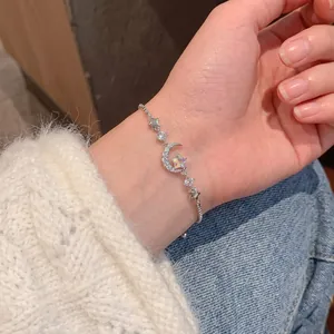 Dettaglio del bracciale con ciondolo luna e stella e zirconi scintillanti al polso