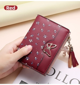 Close-up of a red leather floral wallet with a golden bow buckle and tassel zipper