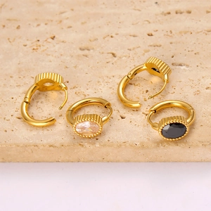 Macro detail of vintage gold hoop earrings with oval zircon inlays on textured stone