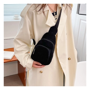 Detailansicht einer schwarzen Cord-Brusttasche getragen über einem beigen Trenchcoat im Herbst