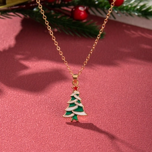 Golden Christmas tree necklace with green enamel on a festive red textured background