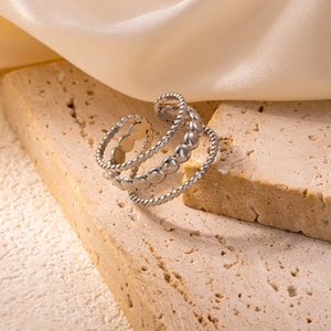 Detail of adjustable silver beaded ring layered on stone and white silk fabric