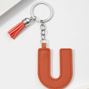 Detail of orange PU leather letter U keychain featuring tassel and silver metal ring
