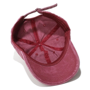 Detail of washed burgundy cotton baseball cap showing interior stitching and metal buckle