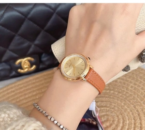 Close-up of gold diamond-set watch with mother-of-pearl dial and brown leather strap