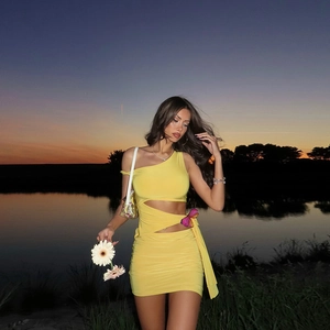 Robe jaune moulante à épaule dénudée avec découpe et nœud sur fond de coucher de soleil