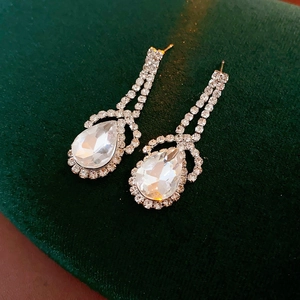 Detailed view of silver teardrop earrings with crystals on luxury green velvet background