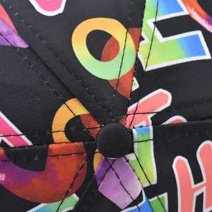 Close-up of the black baseball cap top featuring gradient letter patterns and neat stitching