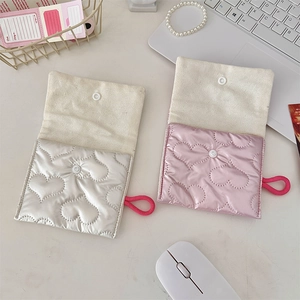 Flat lay of quilted heart mini pouches in silver and pink on a minimalist desk setup