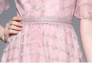Détail de la dentelle rose avec broderie de paillettes et boutons perles sur la robe