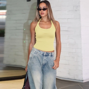 Détail du débardeur en maille jaune clair porté avec un jean denim et des lunettes de soleil