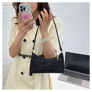 Modèle portant un sac à bandoulière en tweed noir avec texture à carreaux et zip