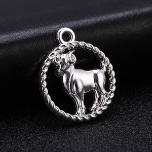 Macro shot of an antique silver Aries zodiac pendant on a dark leather background