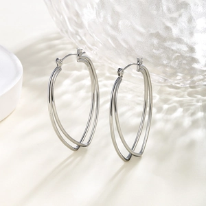 Macro view of silver geometric chain-style hoop earrings on a water ripple glass background