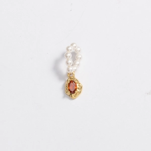Macro detail of golden irregular frame with orange gem and white pearl accent