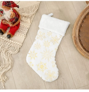 Détail d'une chaussette de Noël blanche à paillettes dorées sur un sol en bois