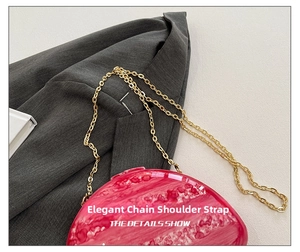 Detail of pink marble pattern acrylic shell clutch with high-gloss finish and gold chain
