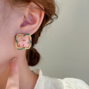 Gros plan sur les boucles d'oreilles carrées rétro avec strass verts et résine rose fleurie